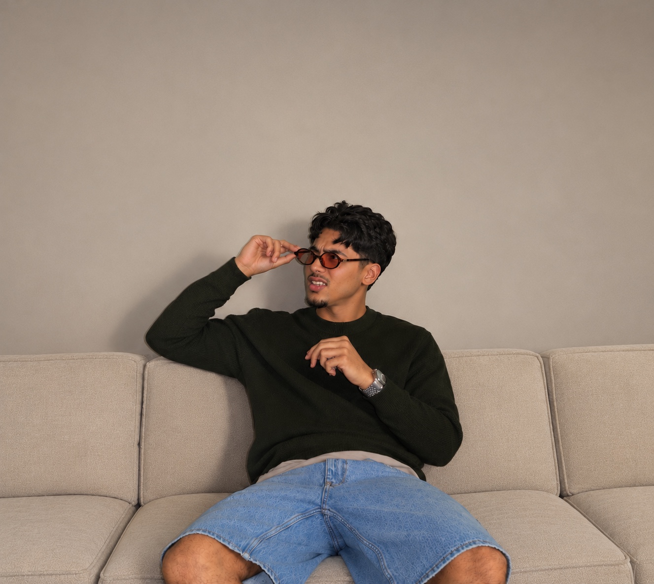 Izaz sitting on a sofa in sunglasses